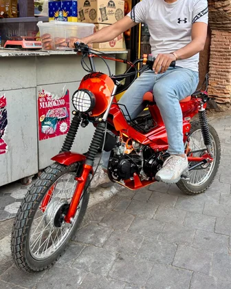 Cadi Ayyad custom red motorcycle with rider near a Marrakech street shop thumbnail