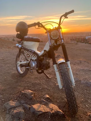 Mouad El Baraka custom Super Cub C90 motorcycle at sunset overlooking Marrakech thumbnail