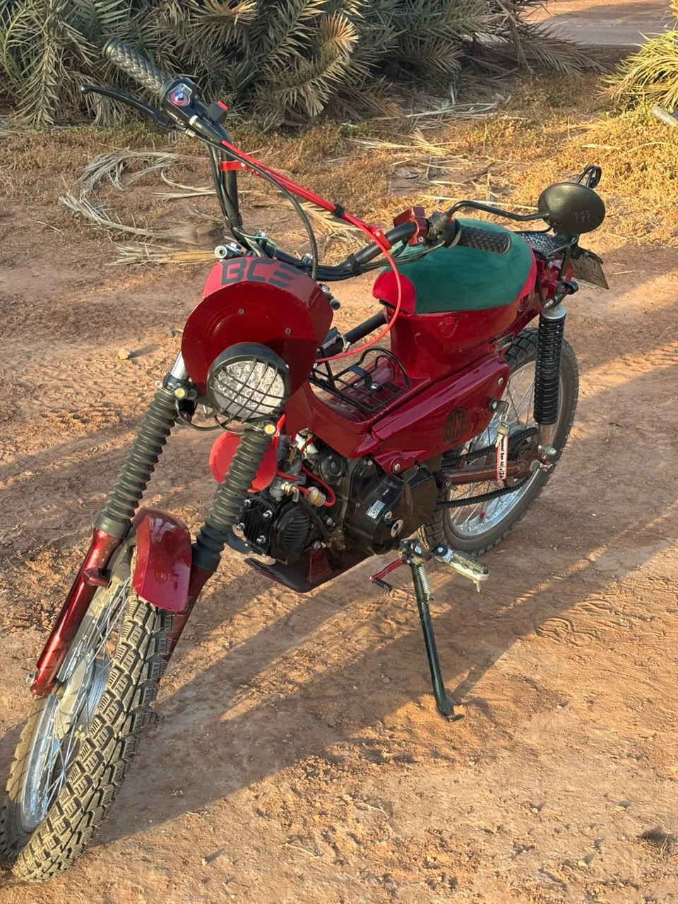 Sidi Youssef Ben Ali custom red motorcycle front three-quarter view on desert terrain