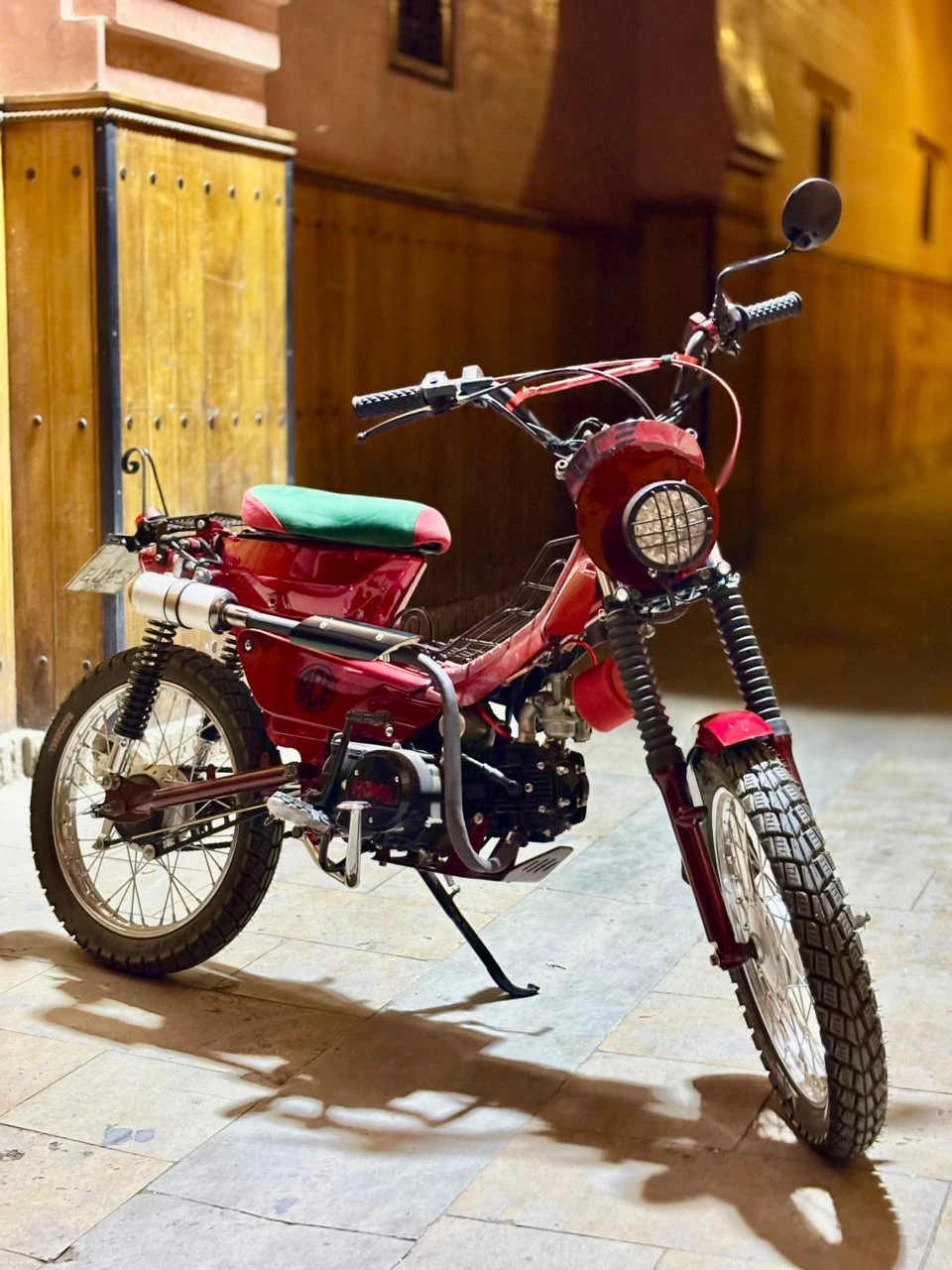 Sidi Youssef Ben Ali custom red motorcycle angled side view under a Marrakech archway