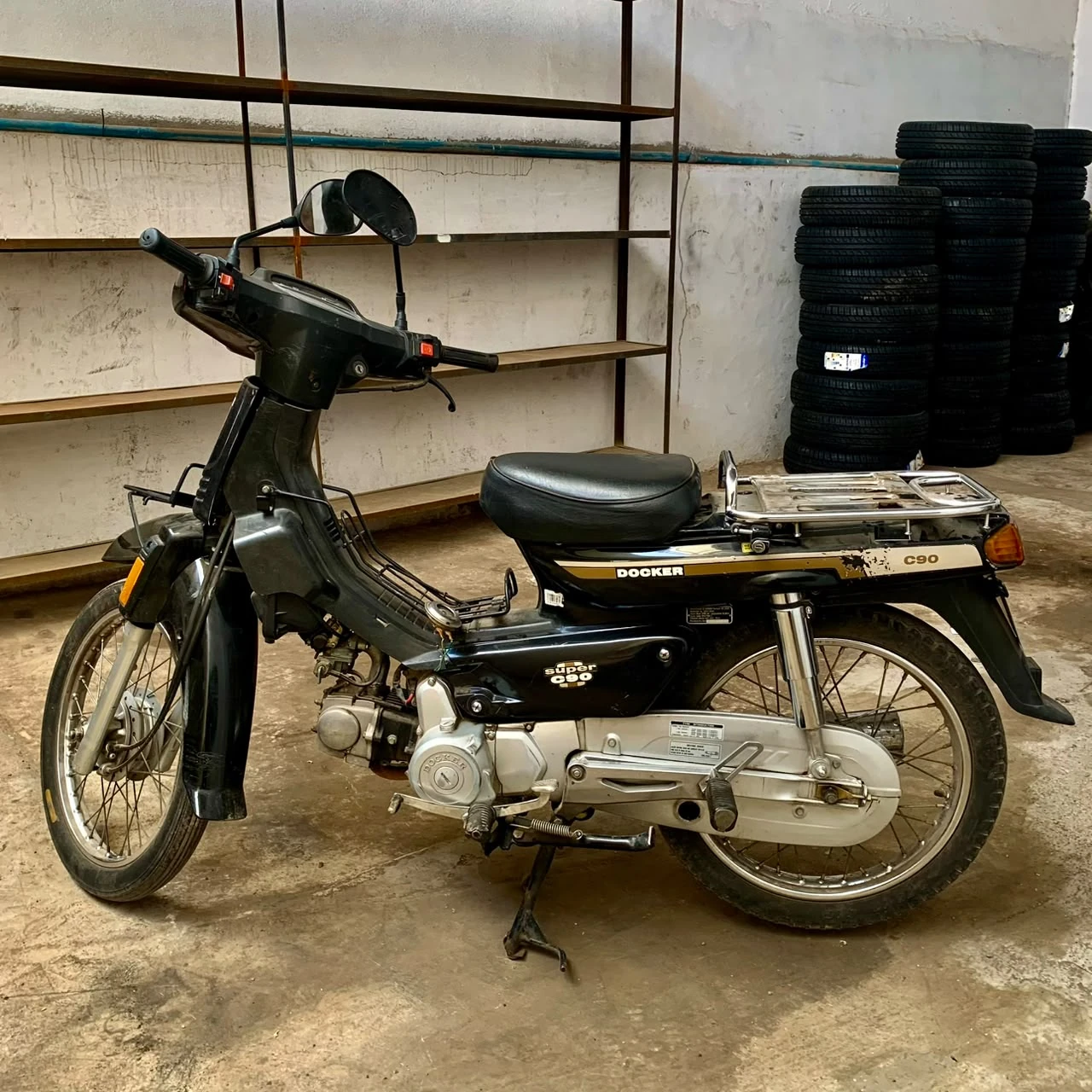 Original black Honda Super Cub C90 donor motorcycle left side view inside the workshop