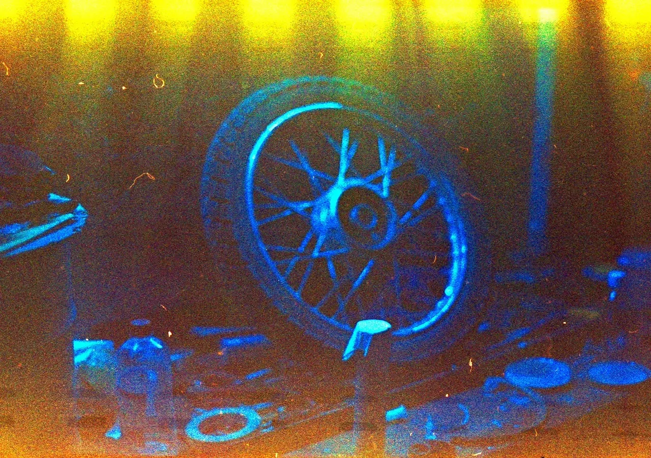 Moody workshop detail featuring a motorcycle wheel under blue and amber light
