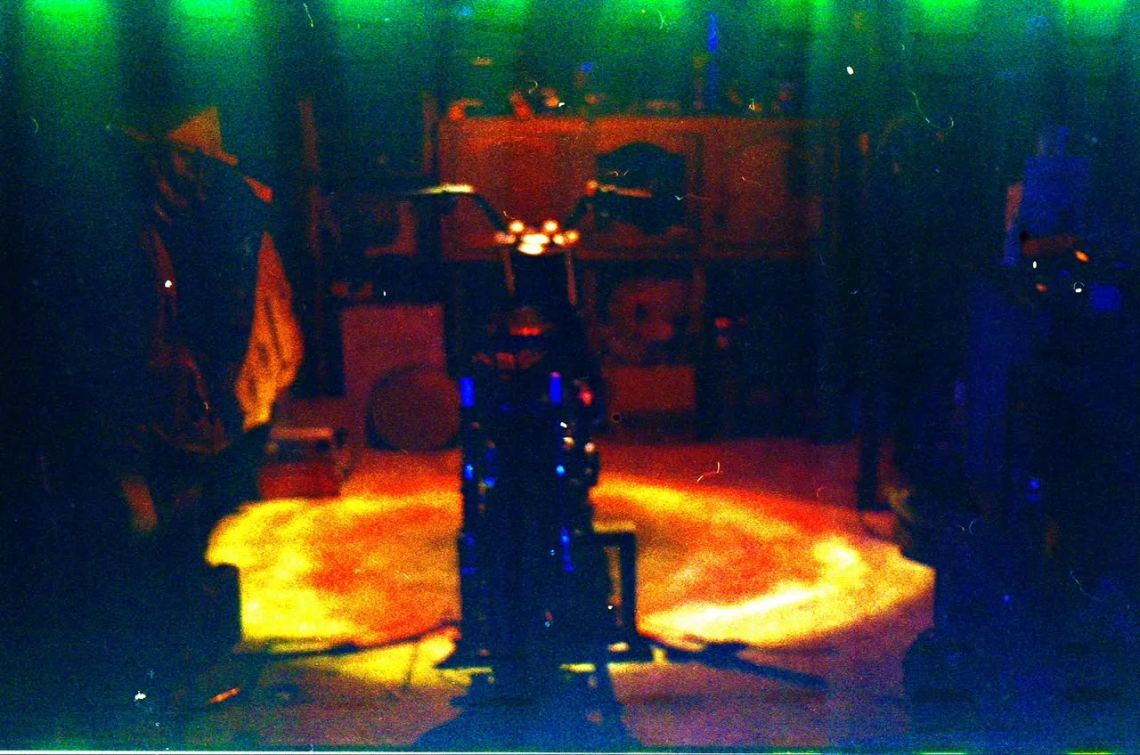 A custom motorcycle build centered inside the BCE workshop under dramatic colored light