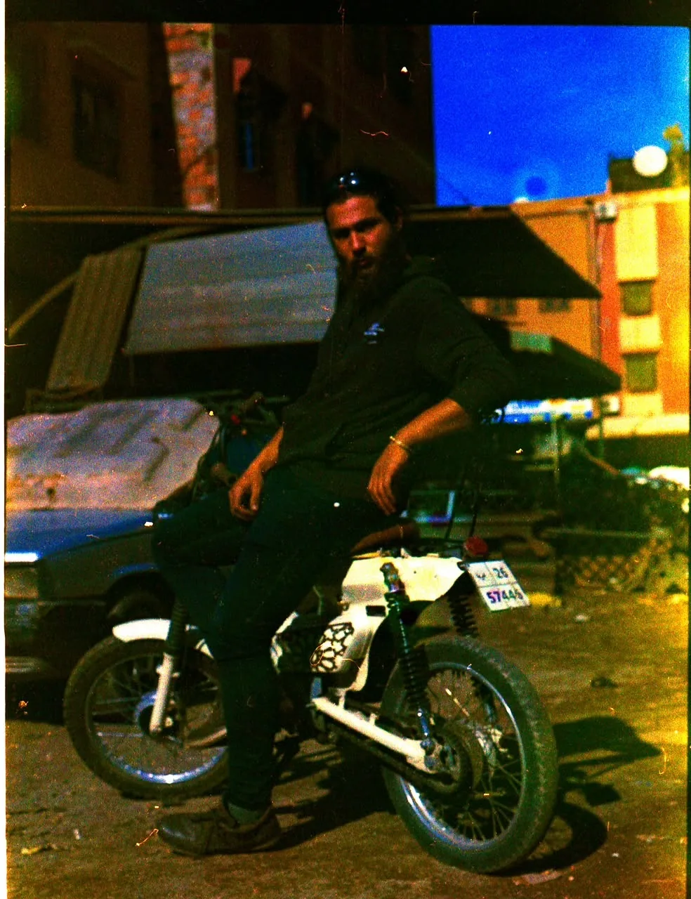 Mouad El Baraka seated on a custom motorcycle outside the workshop at dusk