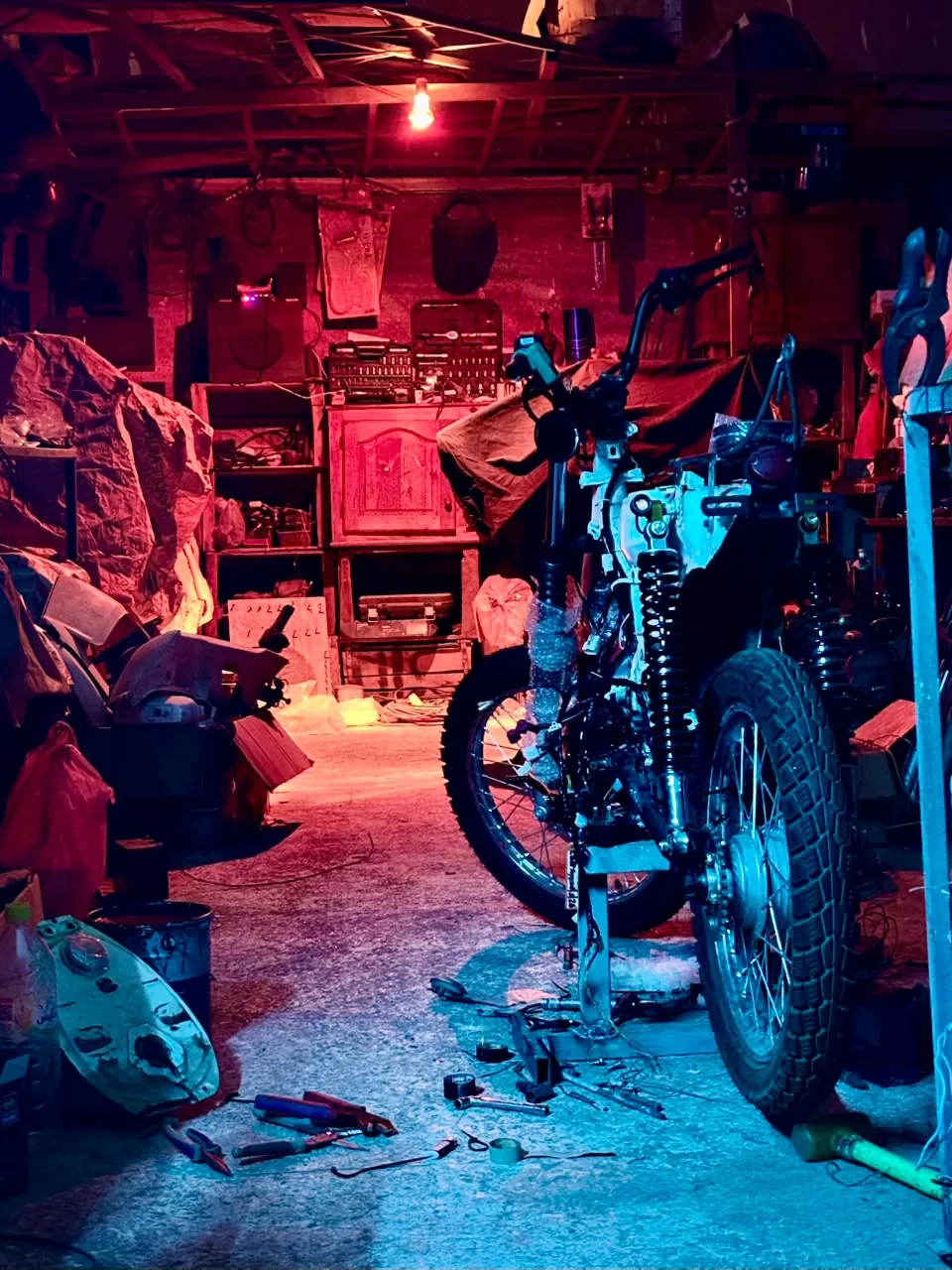 Custom motorcycle project inside the BCE workshop under red and blue lighting