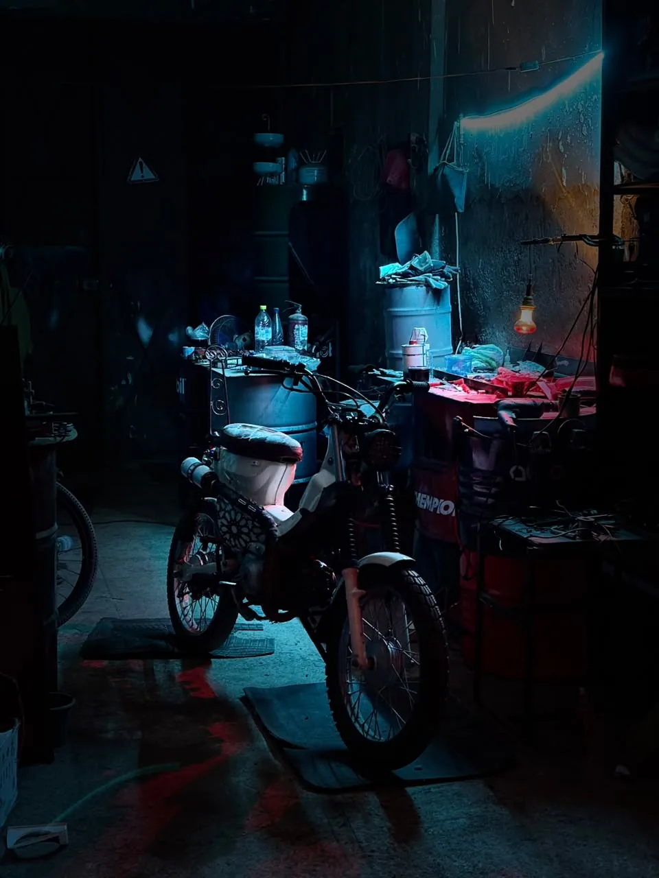 White custom motorcycle parked inside the workshop under moody blue light