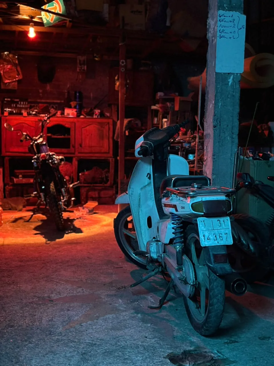 Workshop interior with two motorcycles and a scooter under cinematic colored lighting