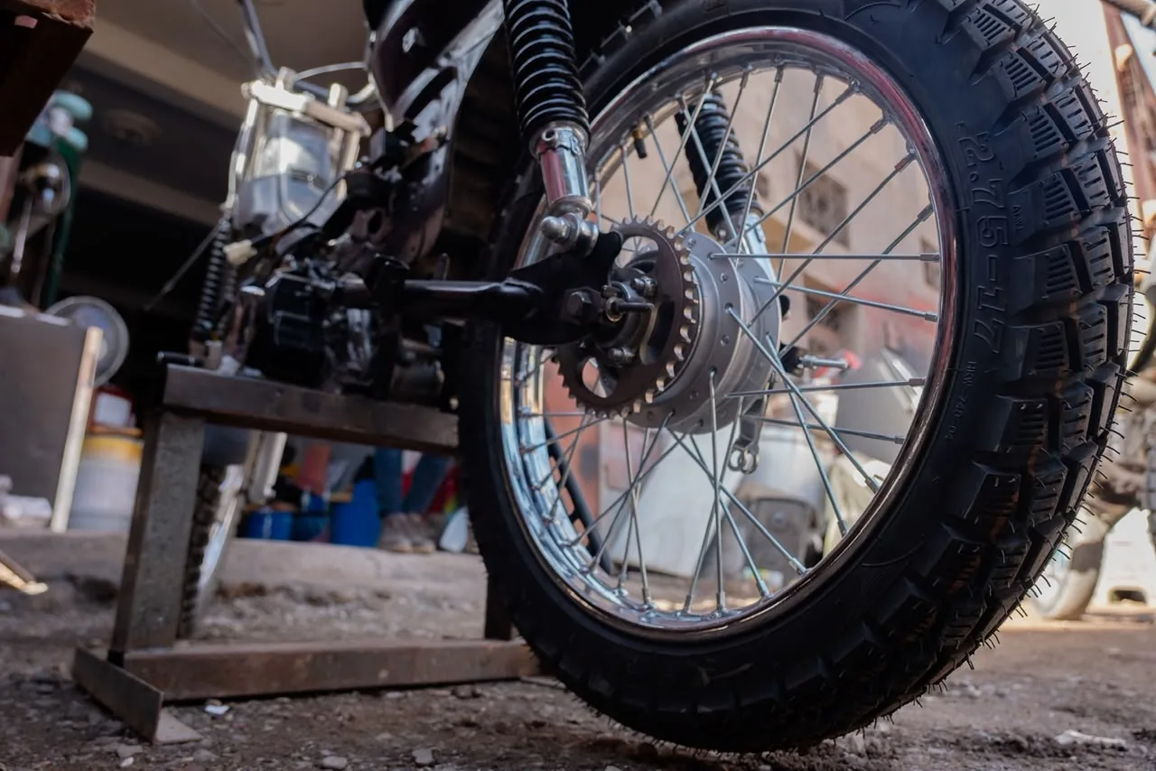 Low-angle detail of a rear wheel and suspension outside the workshop