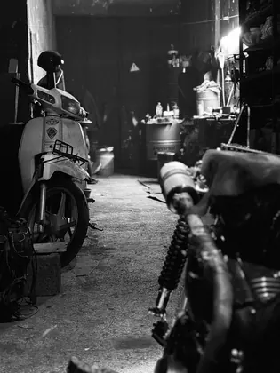 Black and white workshop scene framed between a scooter and a motorcycle thumbnail