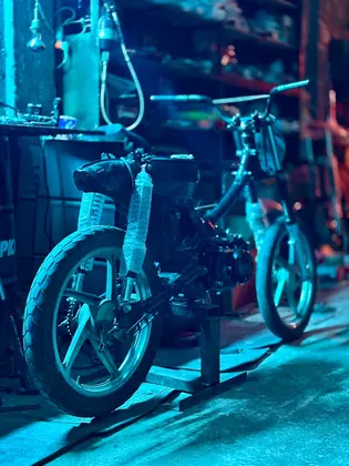 Angled blue-lit view of a stripped-down custom motorcycle frame thumbnail