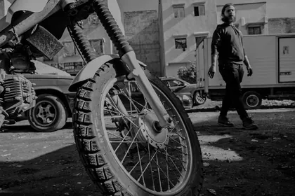 Low-angle black and white shot of a wheel with the creator walking in the background thumbnail